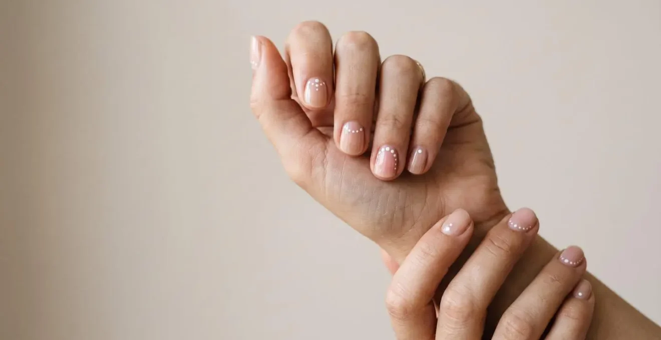 Manos femeninas mostrando uñas decoradas con diseños minimalistas de puntos elegantes creados con punzón