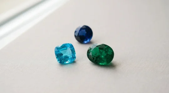 Gemas preciosas de colores vibrantes dispuestas sobre superficie neutra con iluminación natural suave