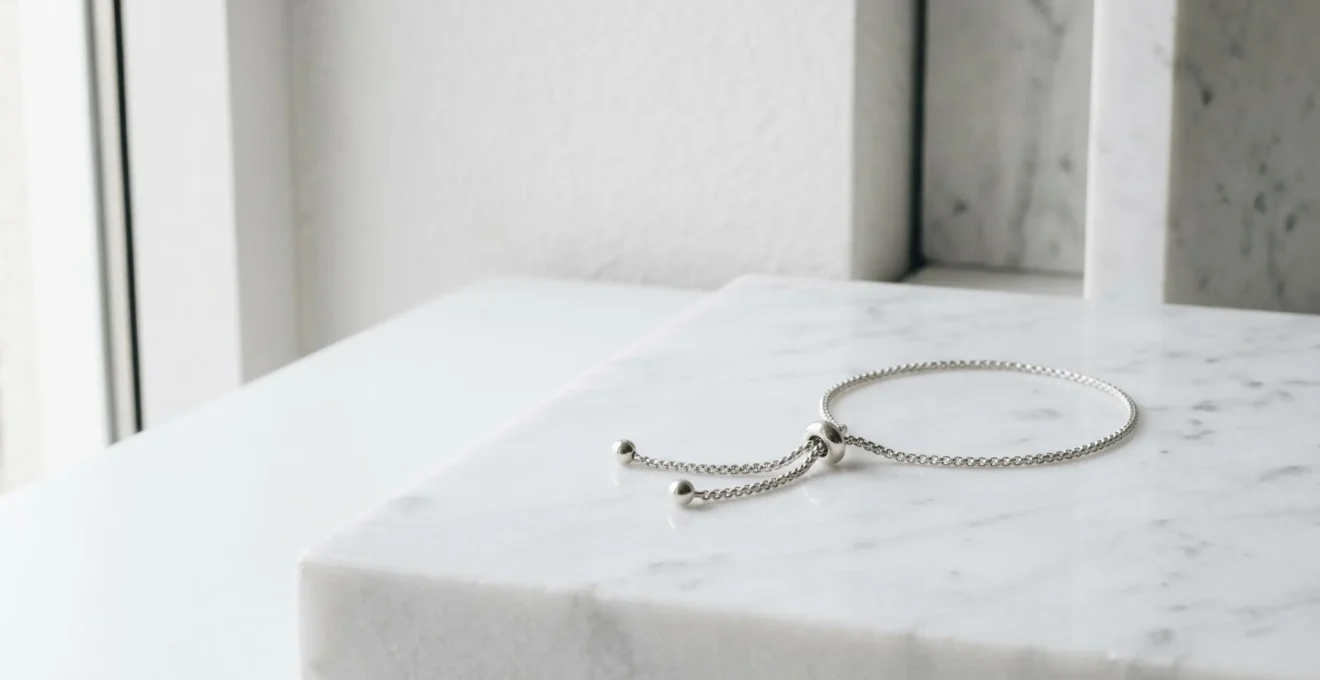 Pulsera ajustable de plata con cierre corredero sobre fondo minimalista con espacio negativo